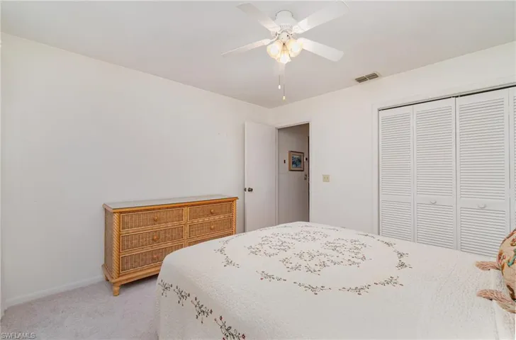 Bedroom featuring light colored carpet, ceiling fan, and a closet
