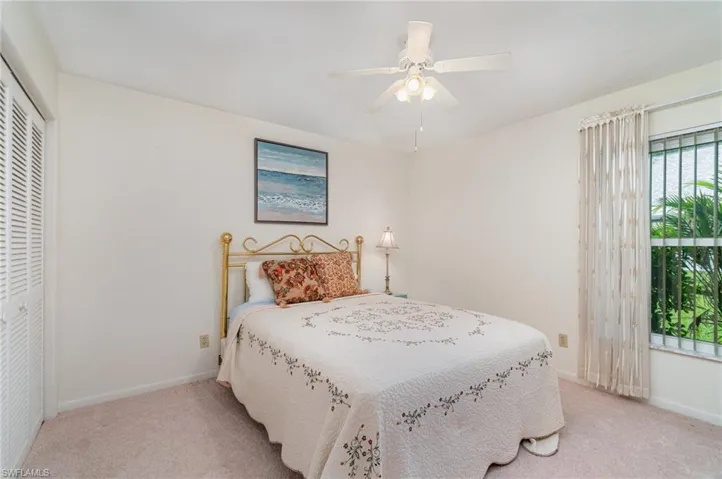 Carpeted bedroom featuring ceiling fan and a closet