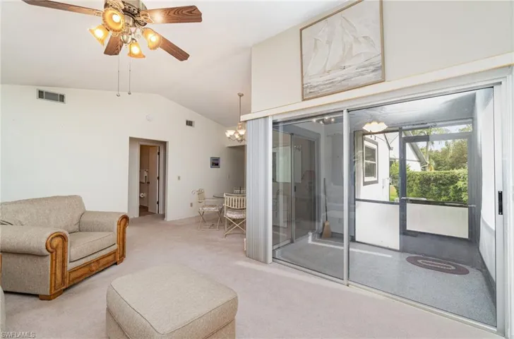 Living area with vaulted ceiling, carpet flooring, a ceiling fan, and a chandelier