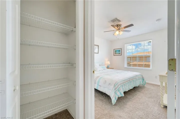 Bedroom featuring a ceiling fan with integrated lighting, a window with horizontal blinds, and carpeting