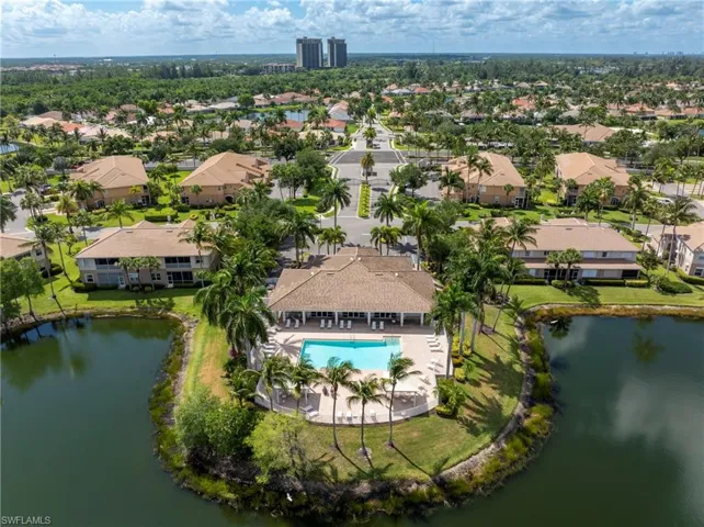 Community clubhouse with an outdoor swimming pool, surrounded by mature palm trees and green landscaping
