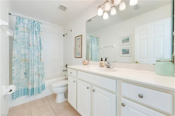 Full guest bathroom featuring a white vanity with integrated sink, a large wall-mounted mirror, and a combination tub/shower