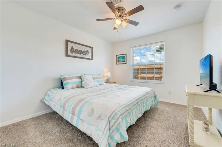 Carpeted guest room featuring a ceiling fan with integrated lighting, a window with horizontal blinds, and white baseboards