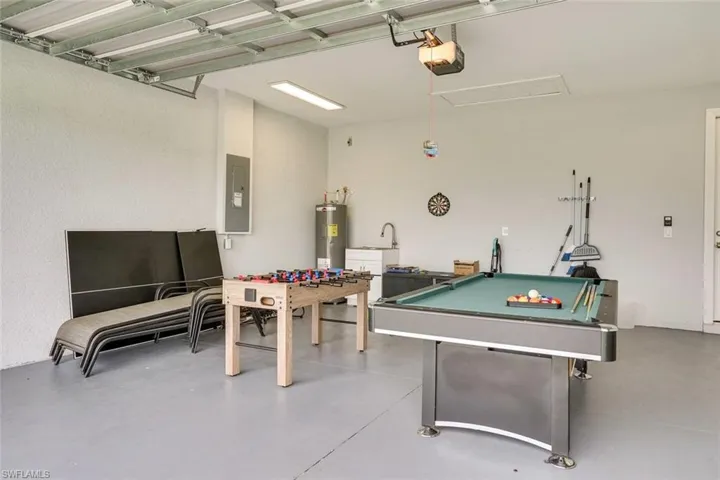 Playroom featuring billiards, electric panel, concrete floors, and electric water heater