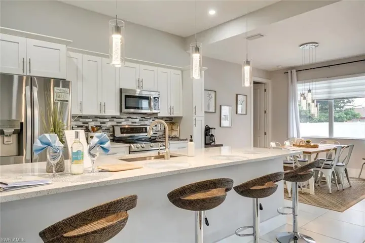 Kitchen with light stone counters, appliances with stainless steel finishes, light tile patterned floors, and decorative backsplash