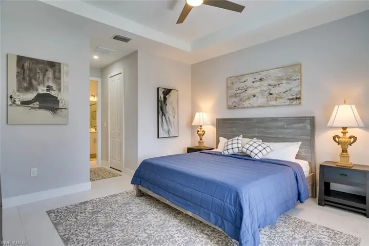 Bedroom featuring light tile patterned flooring, ensuite bathroom, ceiling fan, and a closet
