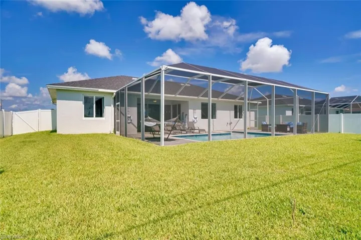 Back of house with a yard, a patio, a fenced in pool, and glass enclosure