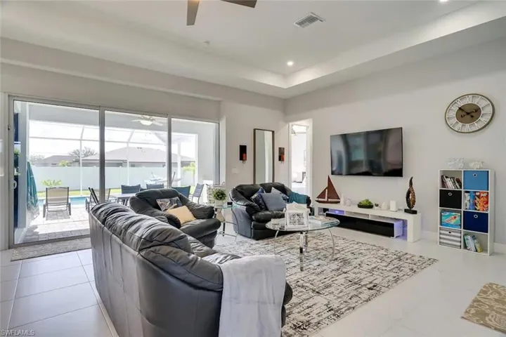 Tiled living room featuring a tray ceiling and ceiling fan