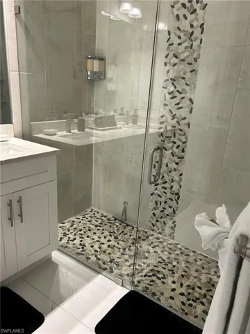 Bathroom featuring tile patterned flooring, walk in shower, and vanity