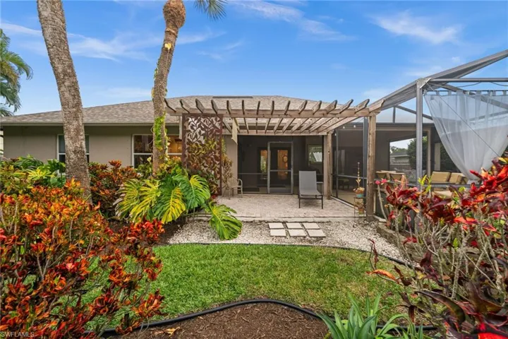 Rear view of property with glass enclosure, a patio, stucco siding, a sunroom, and a pergola