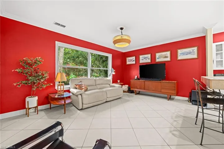 Living area with ornamental molding and light tile patterned flooring