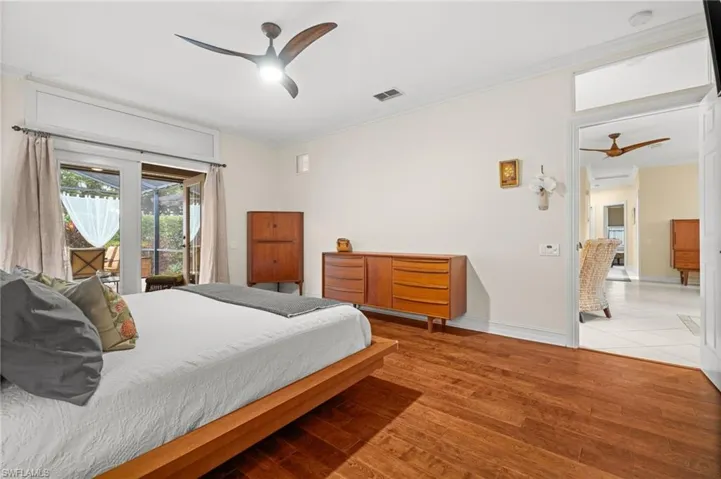 Bedroom featuring crown molding, wood finished floors, access to exterior, and a ceiling fan