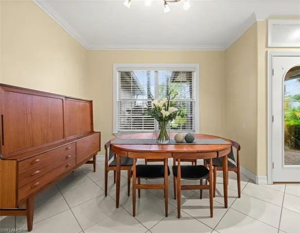 Dining space featuring light tile patterned floors and crown molding