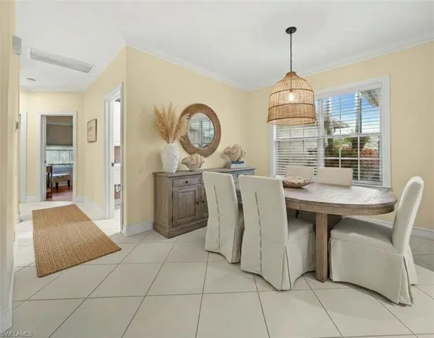 Dining area with light tile patterned flooring and crown molding