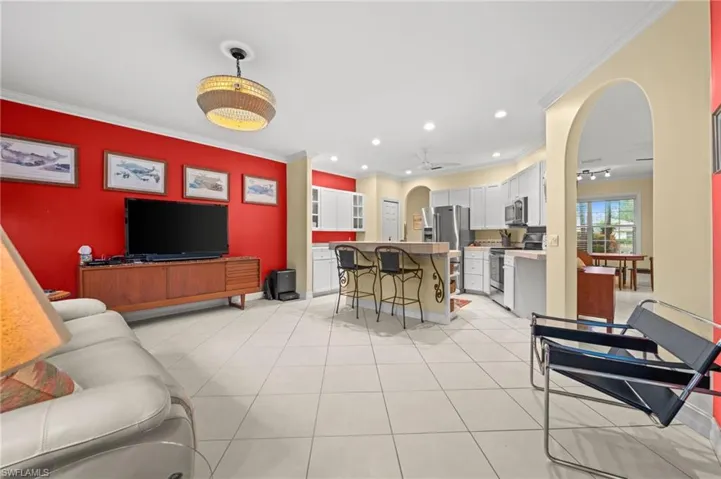 Living room with arched walkways, crown molding, recessed lighting, and light tile patterned floors