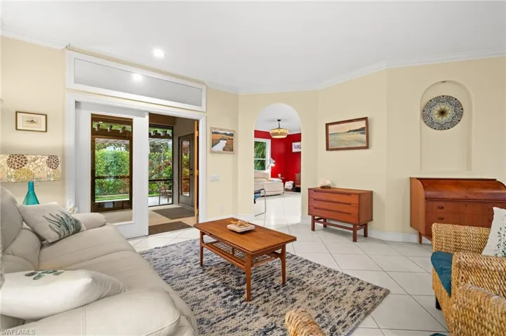 Living area with arched walkways, light tile patterned flooring, and crown molding