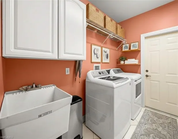 Washroom with washer and clothes dryer, light tile patterned flooring, and cabinet space