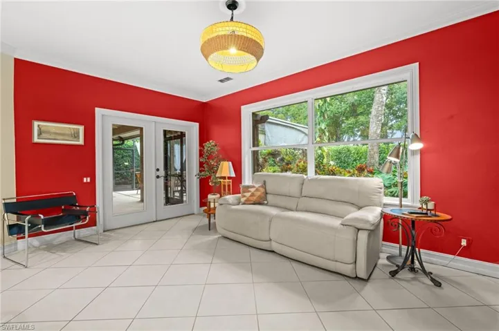 Living room with french doors, ornamental molding, and light tile patterned floors