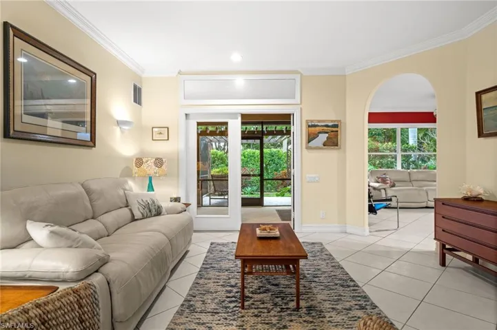 Living area featuring ornamental molding, arched walkways, and light tile patterned floors
