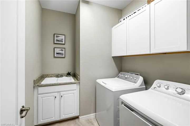 Separate laundry room with sink and cabinetry