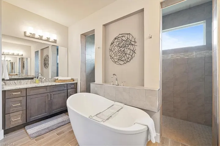 Bathroom featuring a freestanding bath, vanity, wood finished floors, and walk in shower