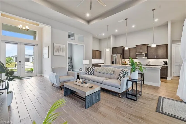 Living area featuring a high ceiling, a chandelier, light wood-style floors, french doors, and recessed lighting