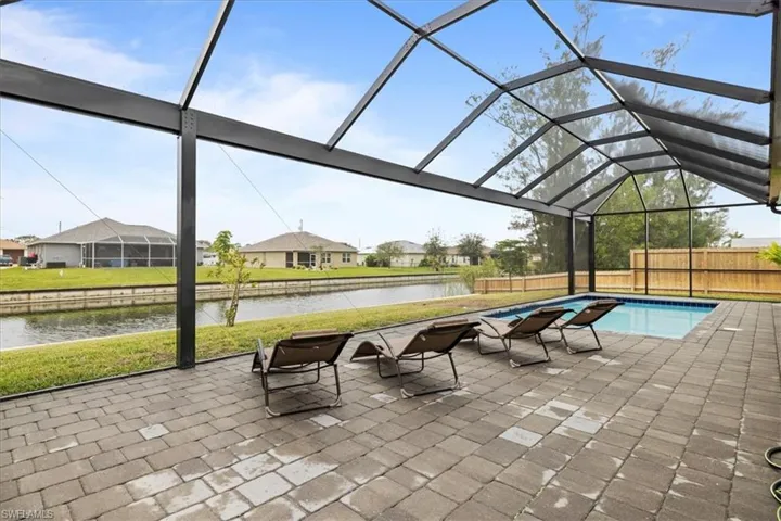 View of pool featuring a water view, a patio, and glass enclosure