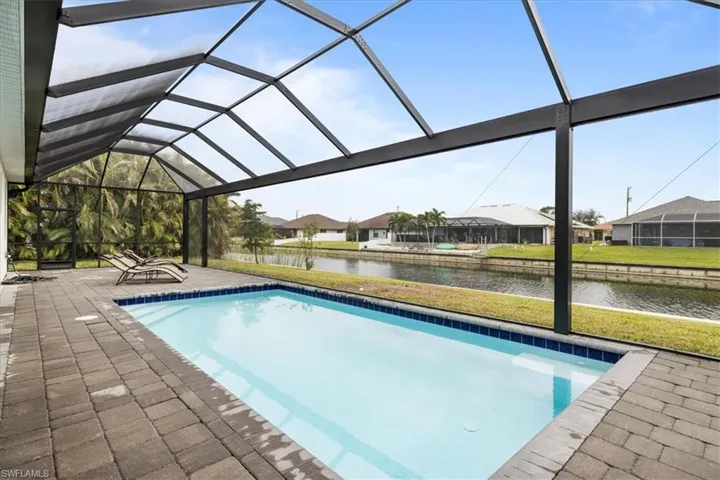 Swimming pool with a water view, a patio, a residential view, and a lanai
