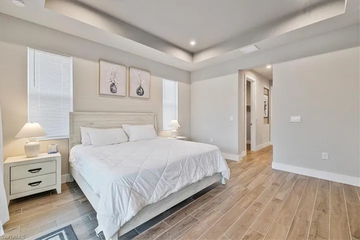 Bedroom featuring a raised ceiling, light wood-type flooring, and recessed lighting