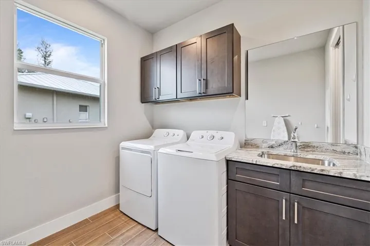 Laundry area with washer and clothes dryer, cabinet space, and light wood-style floors