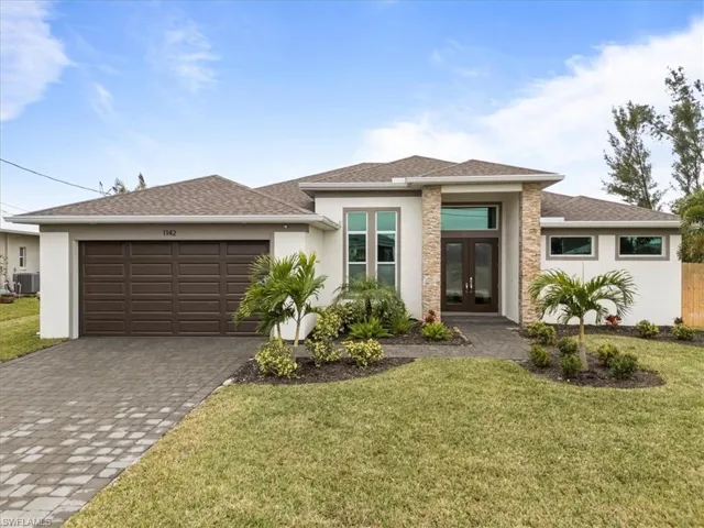 Prairie-style home with french doors, stucco siding, roof with shingles, and decorative driveway