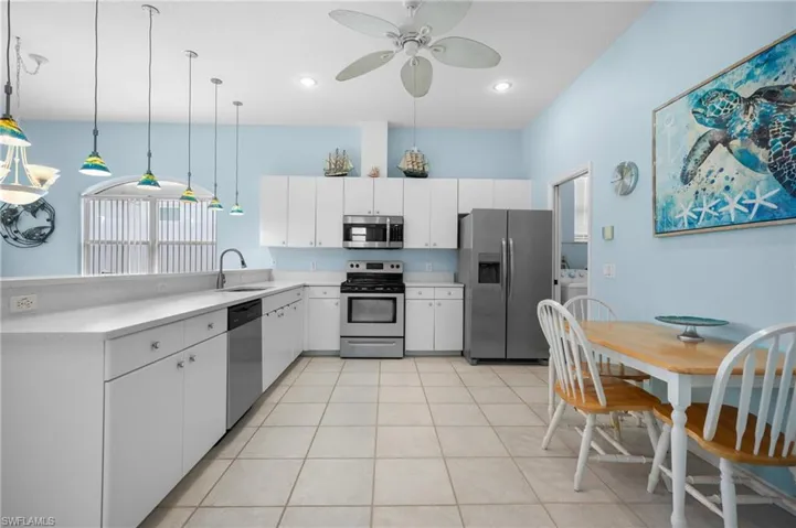 Kitchen featuring white cabinetry, light-toned countertops, stainless steel appliances, and tile flooring