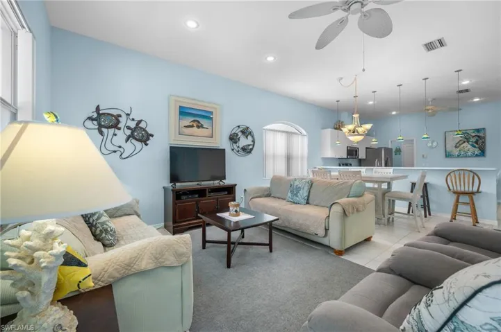 Open-concept living area featuring a ceiling fan, recessed lighting, and an arched window
