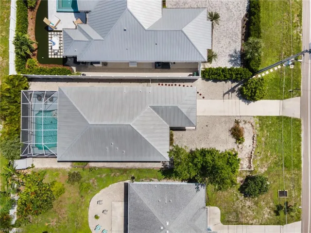 Screen-enclosed swimming pool with a paved patio, complemented by a metal roof structure