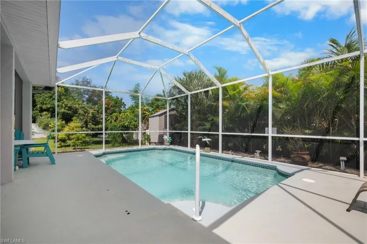Screened outdoor swimming pool with a concrete patio surround and lush perimeter landscaping