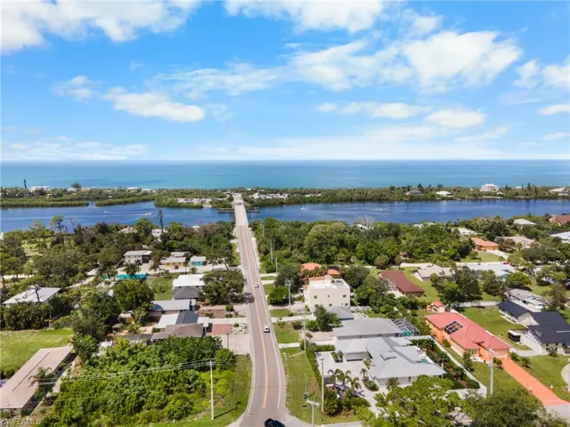 Coastal setting featuring a waterway, bridge, and surrounding residential properties with mature trees