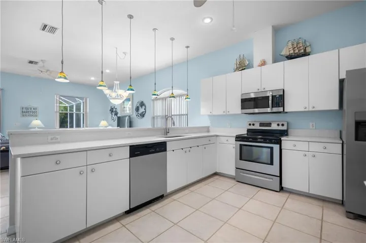 Kitchen featuring white cabinetry, light-toned countertops, stainless steel appliances, and tiled flooring