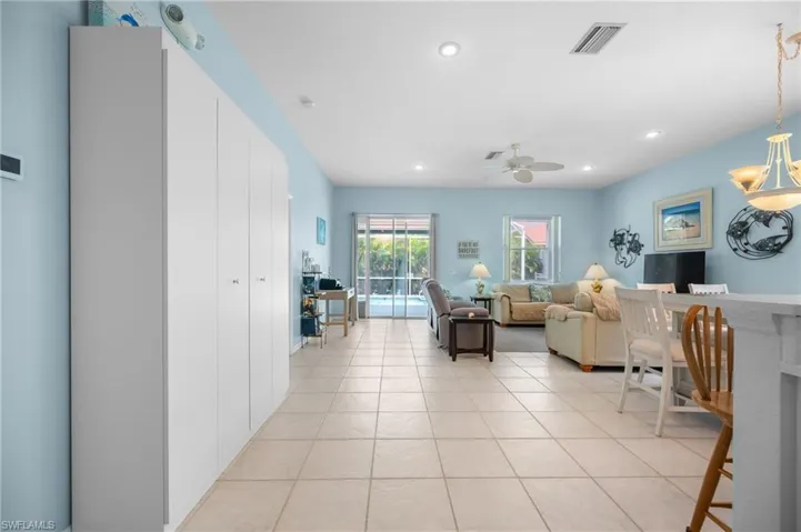 Expansive open-concept living space with large format tile flooring, recessed ceiling lighting, and a ceiling fan