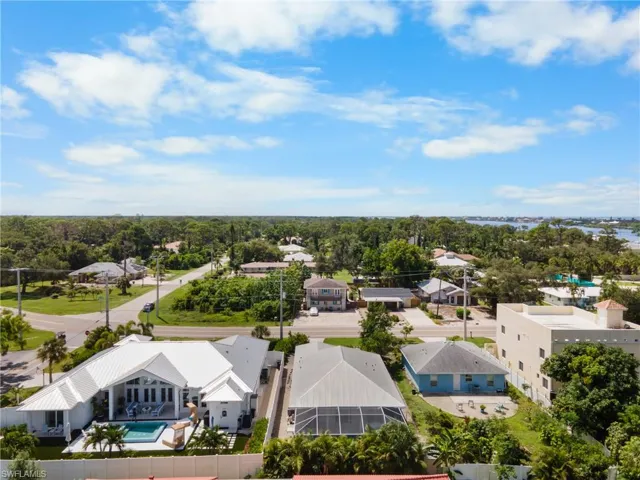 Aerial perspective showcasing the property with a private pool, white exterior, and a metal roof