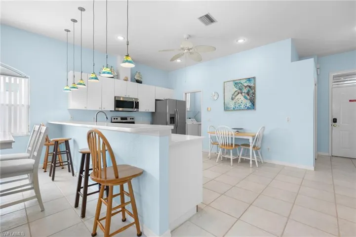 Kitchen featuring white cabinetry, stainless steel appliances, a breakfast bar, recessed lighting, and tile flooring