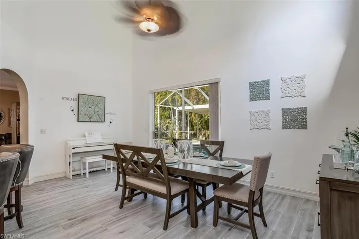 Dining room featuring arched walkways, a towering ceiling, and light wood-style floors