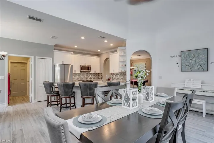 Dining area featuring light wood-style flooring, recessed lighting, ornamental molding, arched walkways, and a chandelier