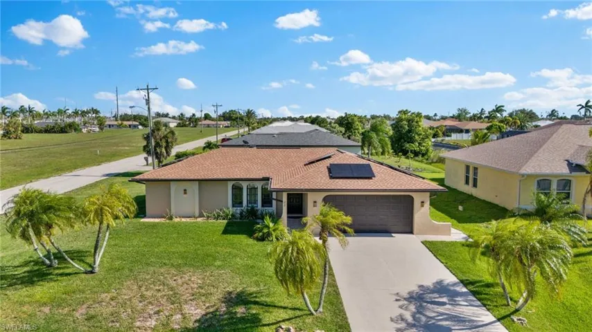 View of front of property featuring a front yard, a garage, and solar panels