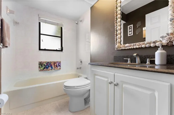 Secondary bathroom with tiled shower / bath, tile flooring, toilet, and vanity