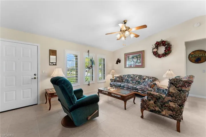 Tiled living room featuring ceiling fan and vaulted ceiling