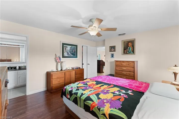 Bedroom with sink, ensuite bath, ceiling fan, and dark hardwood / wood-style floors