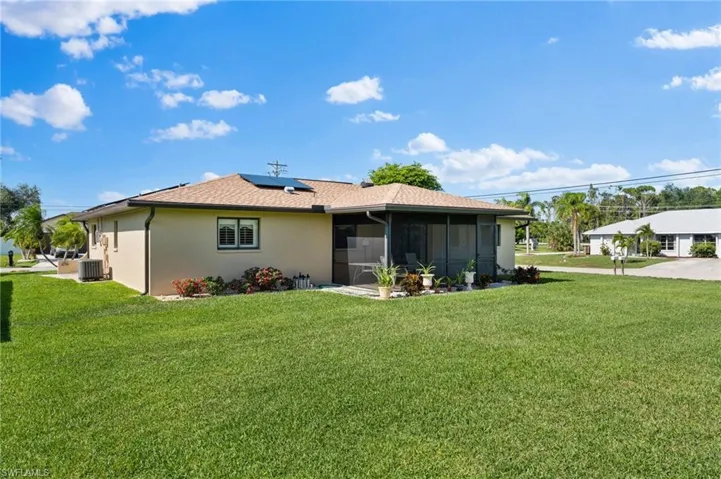 Back of house with a sunroom, a yard, and central AC unit