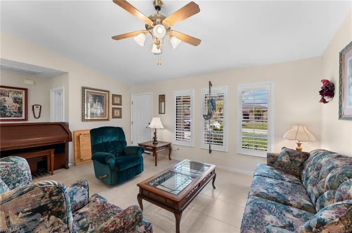 Tiled living room featuring ceiling fan and lofted ceiling