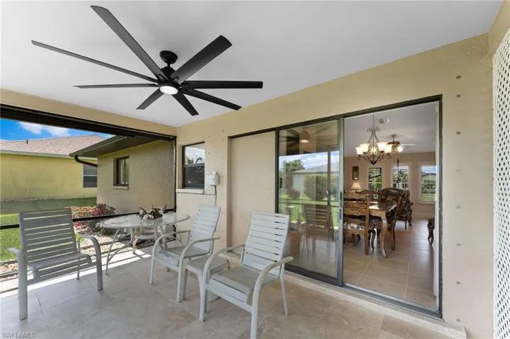 View of screened lanai with ceiling fan and pocketing sliding glass doors into home.