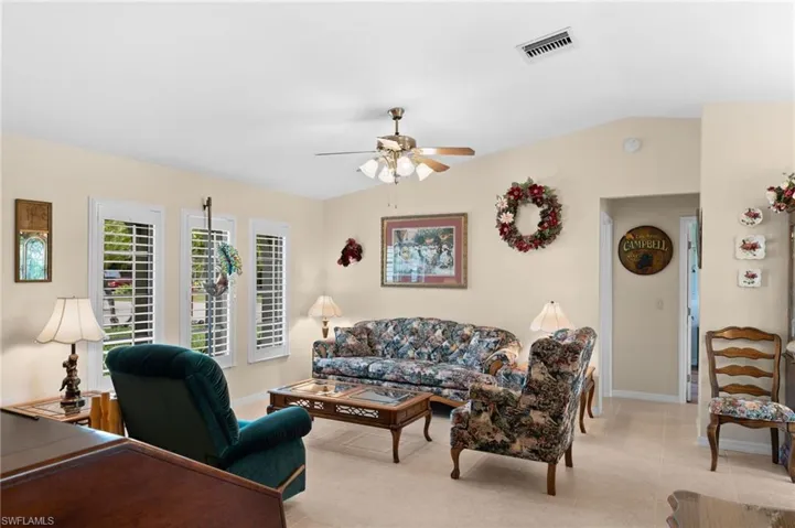 Living room with ceiling fan, vaulted ceiling, and light tile floors